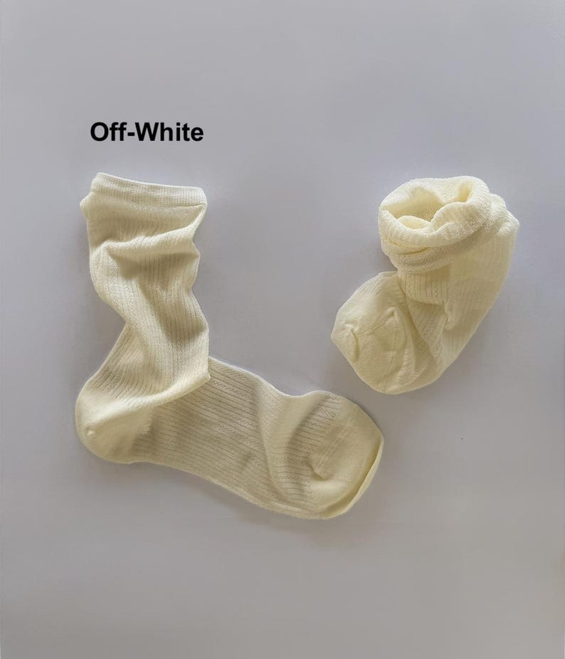 May include: Two off-white socks are shown against a white backdrop. The socks are made of a ribbed knit material. The text "Off-White" is above the socks.