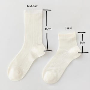 May include: A sock height guide showing two white socks. The mid-calf sock is 16cm long, and the crew sock is 8cm long. The text "Sock Height Guide" is at the top of the image.