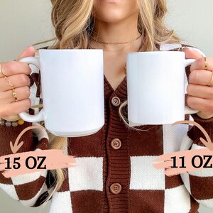 K&ouml;nnte beinhalten: Zwei wei&szlig;e Keramikbecher, einer mit 15 oz und einer mit 11 oz, gehalten von einer Person, die eine braune und wei&szlig;e karierte Strickjacke tr&auml;gt.