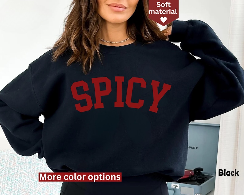 Peut inclure: Sweat-shirt noir avec le mot "SPICY" imprim&eacute; en lettres rouges. Le sweat-shirt a des manches longues et un col rond.