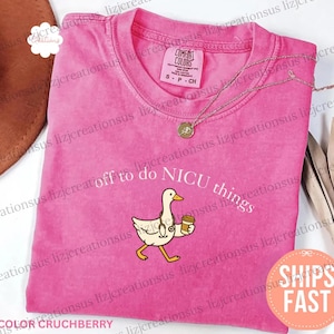 Puede incluir: Una camiseta rosa de manga corta con el gr&aacute;fico de un ganso blanco que lleva un estetoscopio y sostiene una taza de caf&eacute;. El texto sobre el ganso dice off to do NICU things. La camiseta tiene cuello redondo y una etiqueta de Comfort Colors.