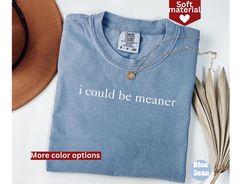 May include: A blue t-shirt with the text "i could be meaner" printed in white. The shirt is made of a soft material and has a distressed look.