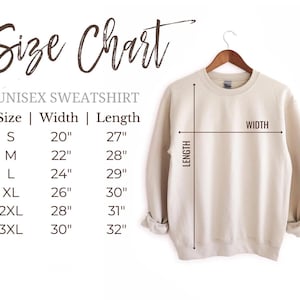 May include: A beige unisex sweatshirt hanging on a wooden hanger, with a size chart displayed to the left. The size chart shows measurements for sizes S to 3XL, with width and length in inches. The text "Size Chart" is at the top.