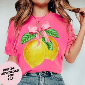 May include: A bright pink t-shirt featuring a watercolor illustration of two yellow lemons with green leaves and a pink bow. The text "DIGITAL DOWNLOAD PNG FILE" is printed on a pink circle in the lower left corner.