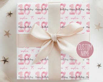 May include: A wrapped gift with a light pink ribbon and bow. The wrapping paper has a repeating pattern of the number "18", the words "Happy Birthday", and the name "sophie". A "Custom Name" sticker is on the gift.