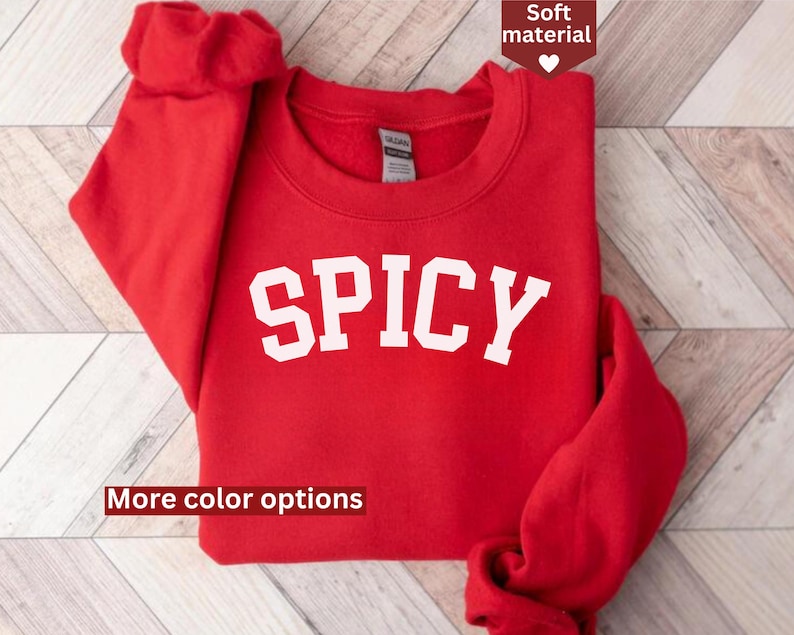Peut inclure: Sweat-shirt rouge avec le mot "SPICY" imprim&eacute; en blanc sur le devant. Le sweat-shirt a un col rond et des manches longues.