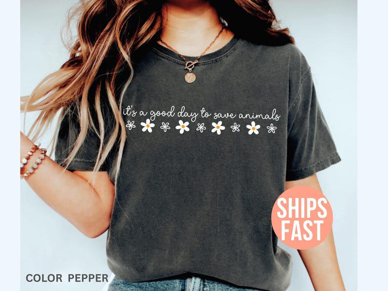 K&ouml;nnte beinhalten: Dunkelgraues T-Shirt mit dem wei&szlig;en Schriftzug "it's a good day to save animals", verziert mit wei&szlig;en G&auml;nsebl&uuml;mchen. Ein l&auml;ssiger, bequemer Kleidungsstil.