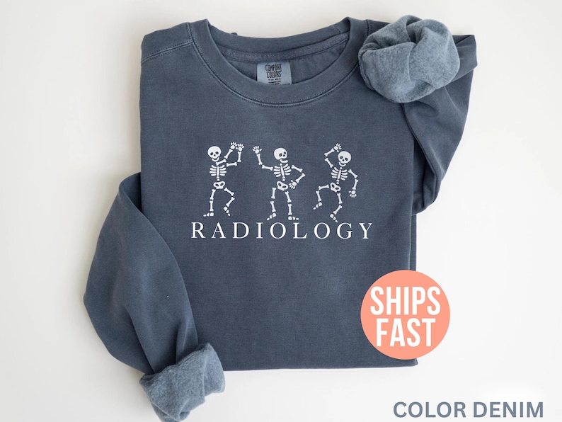 May include: A navy blue sweatshirt with the word "RADIOLOGY" printed in white, below three dancing skeleton figures. The sweatshirt has long sleeves and a crew neck. The text "SHIPS FAST" is on a red circle.