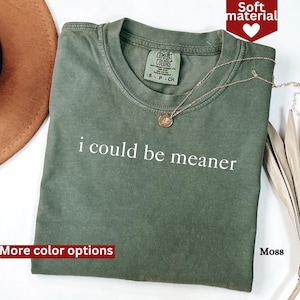 May include: A green t-shirt with the text "i could be meaner" printed in white. The shirt has a relaxed fit and is made of a soft, comfortable material.