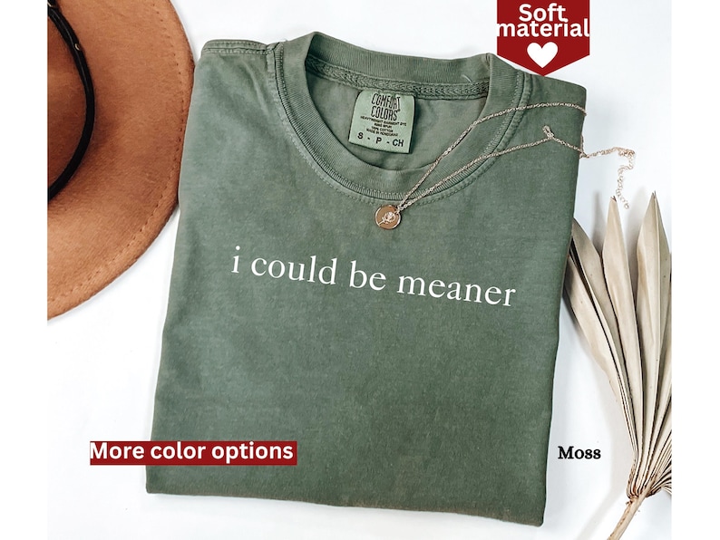 May include: A green t-shirt with the text "i could be meaner" printed in white. The shirt has a relaxed fit and is made of a soft, comfortable material.