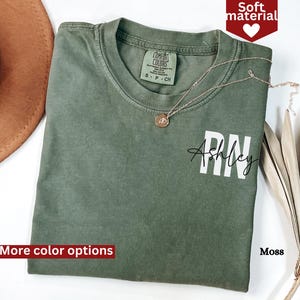 May include: A green t-shirt with the text "RN Ashley" printed on the front. The shirt is made of a soft material and is available in a variety of colors.
