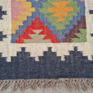 Puede incluir: Alfombra de yute tejida a mano con un patr&oacute;n geom&eacute;trico en rojo, azul, amarillo y verde. La alfombra tiene un borde azul oscuro con un dise&ntilde;o en zigzag blanco y un borde con flecos. Un revestimiento de suelo decorativo.