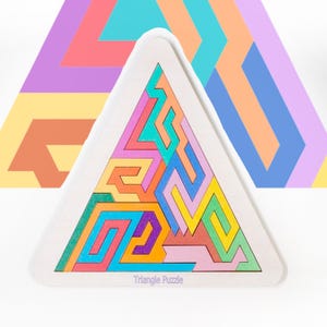 Op de afbeelding: Een houten driehoekpuzzel met een witte rand. De puzzelstukjes zijn in verschillende kleuren, waaronder blauw, groen, oranje en roze. De tekst "Triangle Puzzle" staat onderaan gedrukt. Een groter, abstract driehoekontwerp staat op de achtergrond.