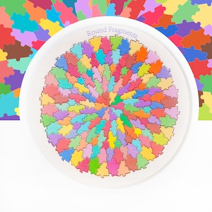 May include: A white plate with a colorful puzzle design. The puzzle is circular, with pieces in various colors including red, blue, green, and yellow. The text "Round Fragments" is printed on the plate.