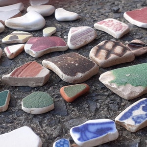 May include: A collection of colorful, broken pieces of ceramic tile. The tiles are various shapes and sizes, and some have patterns or designs.