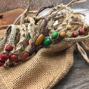May include: A collection of handmade macrame bracelets with colorful beads. The bracelets are made with natural fibers and feature a variety of colors, including red, green, brown, and white.