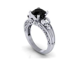 May include: A silver ring with a black gemstone and a skull design. The ring has an intricate, scroll-like design.
