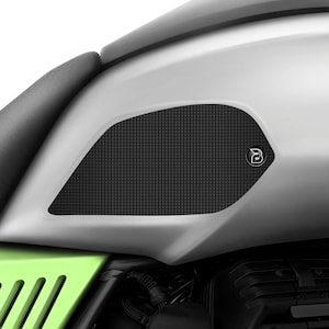 Puede incluir: Protectores de depósito de moto negros con una superficie texturizada y un pequeño logotipo. Los protectores están diseñados para proteger el depósito de arañazos y rozaduras.
