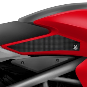 Puede incluir: Primer plano de una motocicleta roja con una almohadilla de tanque texturizada negra. La almohadilla del tanque tiene un pequeño logotipo en el lado derecho.