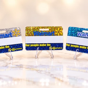 May include: Three rectangular name badges featuring a glittery finish in silver, gold, and blue. Each badge displays the blue Walmart logo, a white horizontal stripe, and the text Our people make the Difference in yellow lettering on a blue base.
