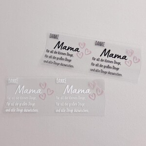 Könnte beinhalten: Drei transparente Aufkleber mit dem Text "Danke Mama" und rosa Herzen. Der Text lautet "Danke Mama, für all die kleinen Dinge, für all die großen Dinge und alle Dinge dazwischen."