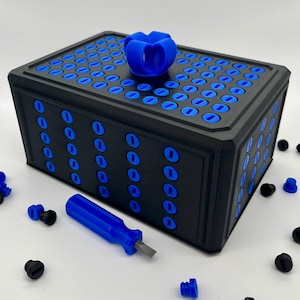 May include: A rectangular black storage box featuring a grid of blue circular inserts on the top and sides, topped with a blue four-petaled handle. A small blue screwdriver with a flat metal tip is positioned in front of the box, surrounded by loose black and blue circular screw-like components.