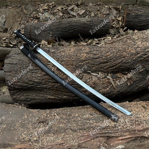 May include: A katana sword with a silver blade and black handle and scabbard. The sword is resting on a bed of wood logs and sawdust. The handle has a white and black pattern.