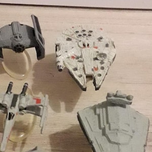 以下が含まれることがあります： ミレニアム・ファルコン、Xウイング、TIEファイター、インペリアルスターデストロイヤーなど、ミニチュアのスターウォーズ宇宙船のコレクション。宇宙船はプラスチック製で、象徴的な色で塗装されています。