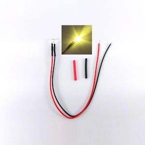 Könnte beinhalten: Eine gelbe LED-Lichtkomponente mit angeschlossenen roten und schwarzen Drähten, die an der Basis der Glühbirne mit schwarzem Schrumpfschlauch versehen ist. Das Set enthält zwei zusätzliche Stücke roten und schwarzen Schrumpfschlauch und ein Inset.
