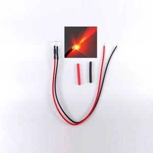 Könnte beinhalten: Eine transparente LED mit roten und schwarzen Drähten und einem roten Schrumpfschlauch. Ein kleines inset-Bild zeigt die rot leuchtende LED. Die Drähte sind mit der LED verbunden, und die Schrumpfschläuche sind separat.