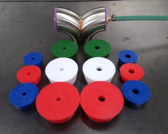 May include: A set of 12 rubber plugs in various sizes and colors, including red, white, blue, and green. The plugs have a central hole and are arranged in a semi-circle pattern on a gray surface. A stainless steel pipe fitting is also visible in the image.