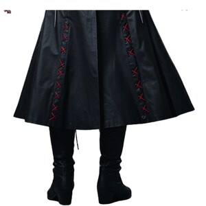 May include: Black faux leather coat with red cross-stitch detailing on the sides. The coat has a flared skirt and is paired with black leggings and wedge boots. The overall style is gothic and edgy.
