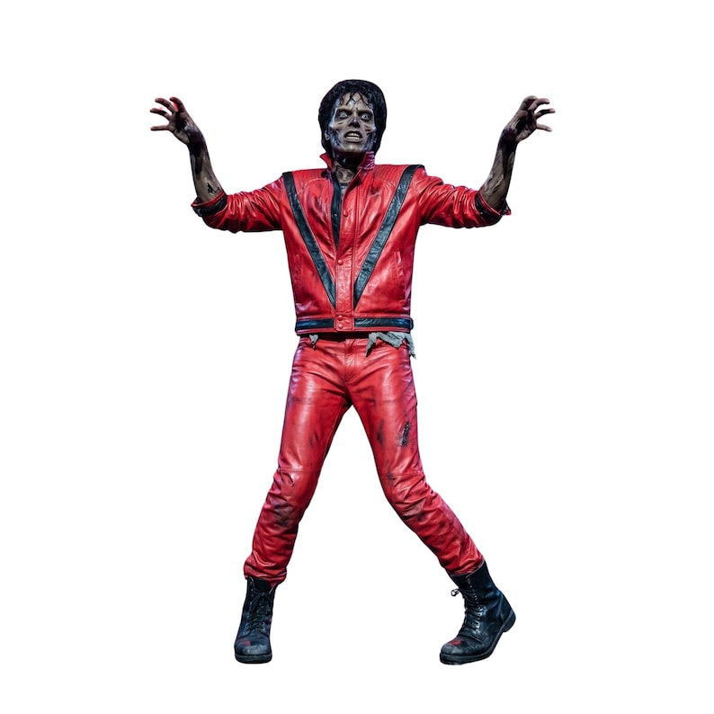 May include: A zombie figure wearing a red leather jacket with black V-shaped accents and matching red leather pants. The figure has dark hair, pale grey skin with dark shading, and black boots, posed with arms raised and fingers curled in a claw-like gesture.