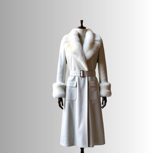 May include: A long white coat with a large fur collar and fur cuffs. The coat has a belt and two pockets.