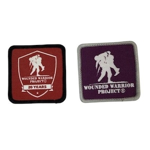 May include: Two embroidered patches. One is square with a red background and black border, featuring a white graphic of two figures and text that reads "Wounded Warrior Project" and "20 YEARS". The other patch is square with a purple background and a white graphic of two figures, with the text "Wounded Warrior Project".
