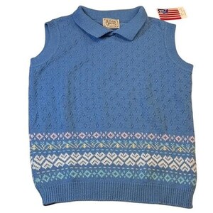 May include: A sleeveless blue knit sweater with a collared neckline. The sweater features a patterned design in white, blue, yellow, and purple at the bottom. A tag with an American flag is attached.