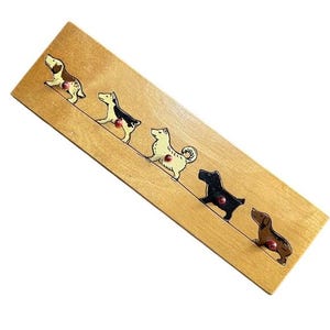 May include: Wooden dog-themed wall decor featuring five different dog breeds in various colors. Each dog has a red dot and is arranged diagonally on a light brown wooden plank. A charming and unique piece for dog lovers.