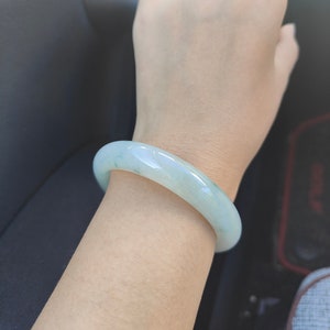 May include: A light green jade bangle bracelet. The bracelet is smooth and polished.
