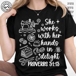 Könnte beinhalten: Schwarzes T-Shirt mit weißer Grafik einer Nähmaschine, Nähutensilien und dem Text "She works with her hands in delight Proverbs 31:13." Das Design umfasst Garnrollen, Stoff und eine Schere.
