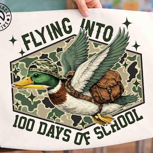 Pu&ograve; includere: Borsa tote bianca con un'anatra dei cartoni animati che indossa un cappello e uno zaino mimetico, che tiene una matita. Il testo recita "FLYING INTO 100 DAYS OF SCHOOL" in verde. L'anatra &egrave; ambientata su uno sfondo mimetico.