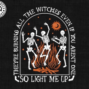 Puede incluir: Diseño gráfico negro con tres esqueletos bailando alrededor de una hoguera, con el texto "They're burning all the witches even if you aren't one, so light me up." Incluye formatos SVG, EPS, DXF y PNG.