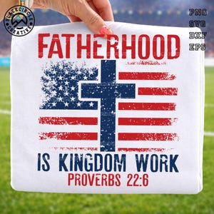 May include: A white t-shirt featuring the red text FATHERHOOD at the top and IS KINGDOM WORK PROVERBS 22:6 at the bottom. In the center is a distressed graphic of the American flag with a dark blue cross superimposed over the stars and stripes.