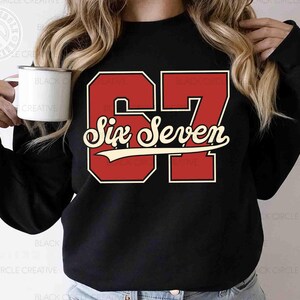 May include: Black sweatshirt featuring the number "67" in red with a white outline and the words "Six Seven" in a cursive font. The design is a vintage style. The image also includes the text "SVG EPS DXF PNG".