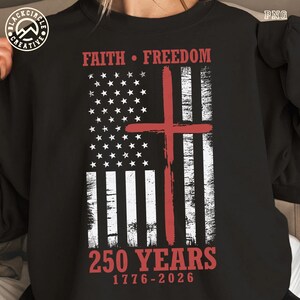 Puede incluir: Sudadera negra con un dise&ntilde;o desgastado de la bandera estadounidense y una cruz roja. Las palabras "FAITH &bull; FREEDOM" est&aacute;n encima de la bandera, y "250 YEARS 1776-2026" debajo. Una prenda de tem&aacute;tica patri&oacute;tica y religiosa.