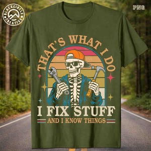 May include: Olive green t-shirt with a graphic of a skeleton wearing sunglasses and a cap, holding a wrench and hammer. Text reads "THAT'S WHAT I DO, I FIX STUFF AND I KNOW THINGS."
