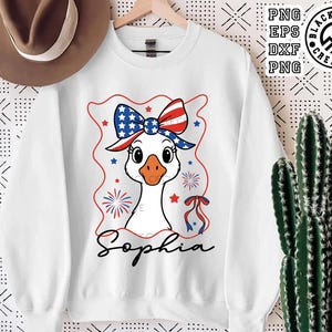 May include: White sweatshirt with a cartoon goose wearing a red, white, and blue bow and a red, white, and blue headband. The goose is surrounded by fireworks and stars. The text "Sophia" is printed below the goose.