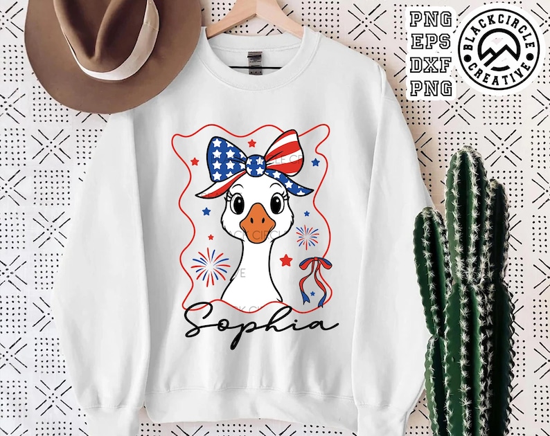 May include: White sweatshirt with a cartoon goose wearing a red, white, and blue bow and a red, white, and blue headband. The goose is surrounded by fireworks and stars. The text "Sophia" is printed below the goose.