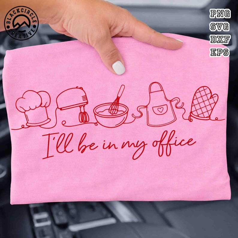 Puede incluir: Camiseta rosa con un dibujo lineal rojo de gorro de chef, batidora, cuenco con batidor, delantal y manopla de horno. El texto "I'll be in my office" est&aacute; debajo. La camiseta est&aacute; sujeta por una mano.