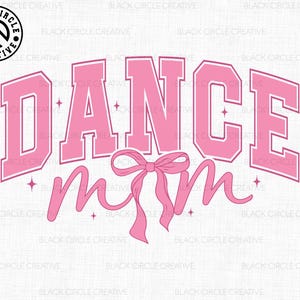 May include: Pink graphic with the text "DANCE mom" in a varsity style font. A pink ribbon with a bow is below the text.
