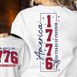 Könnte beinhalten: Weißes Sweatshirt mit dem Text "America 1776 250 Years of Freedom" in Rot und Blau. Das Design befindet sich auf der Rückseite und der Vorderseite des Shirts. Das Design enthält Sterne und die Zahl 1776.